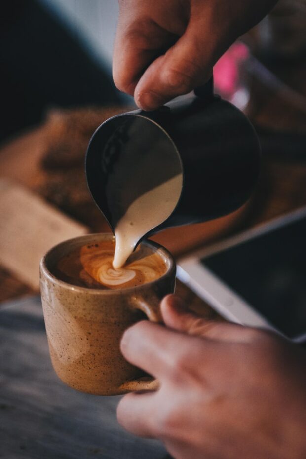 focused photograph of froth pouring into mug of coffee
